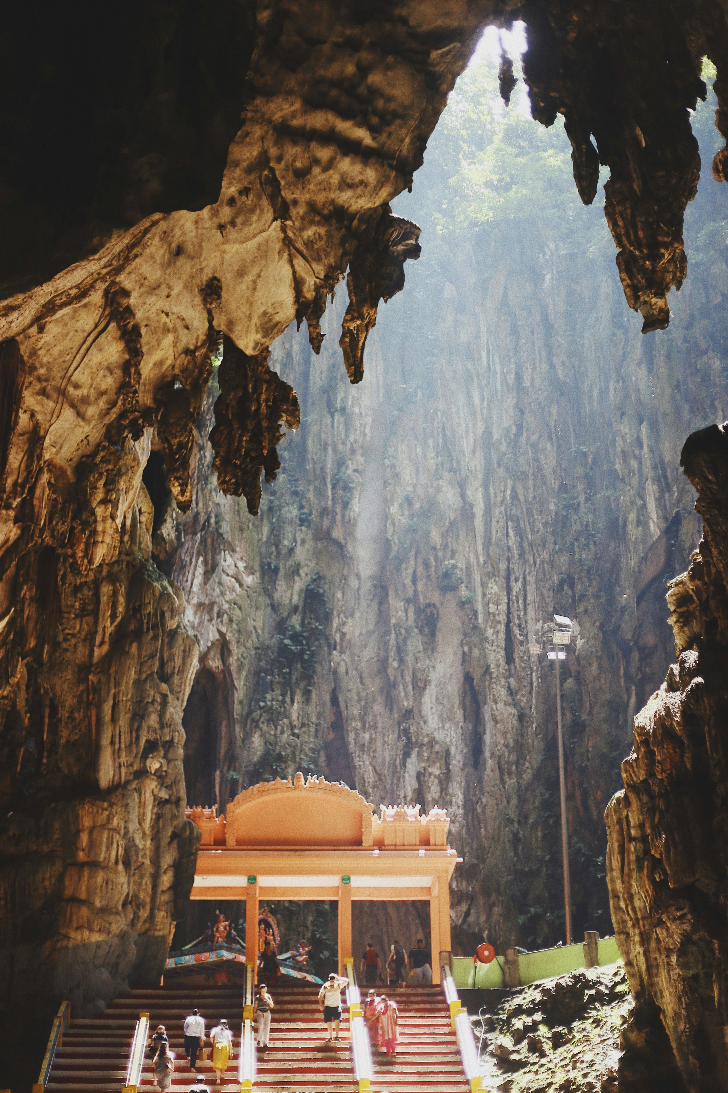 people climbing up stairs towards temple in cave